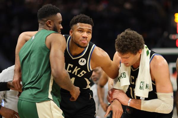 Giannis Antetokounmpo #34 of the Milwaukee Bucks is helped off the court by Thanasis Antetokounmpo #43 and Brook Lopez #11 after suffering an injury during the second half of a game against the Boston Celtics at Fiserv Forum on April 09, 2024