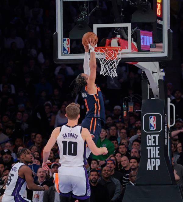 Knicks guard Jalen Brunson #11 slams the ball as Sacramento Kings forward Domantas Sabo<em></em>nis #10 watches