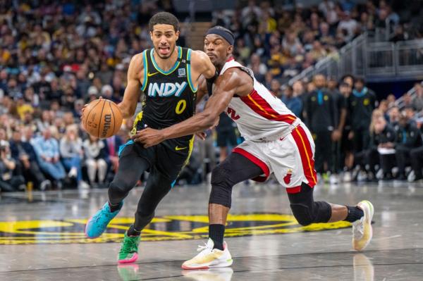 Pacers guard Tyrese Haliburton (0) drives against the defense of Miami Heat forward Jimmy Butler