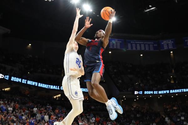 Jimmy Clark III of the Duquesne Dukes shooting a basketball over Spencer Johnson of the Brigham Young Cougars during an NCAA Tournament game